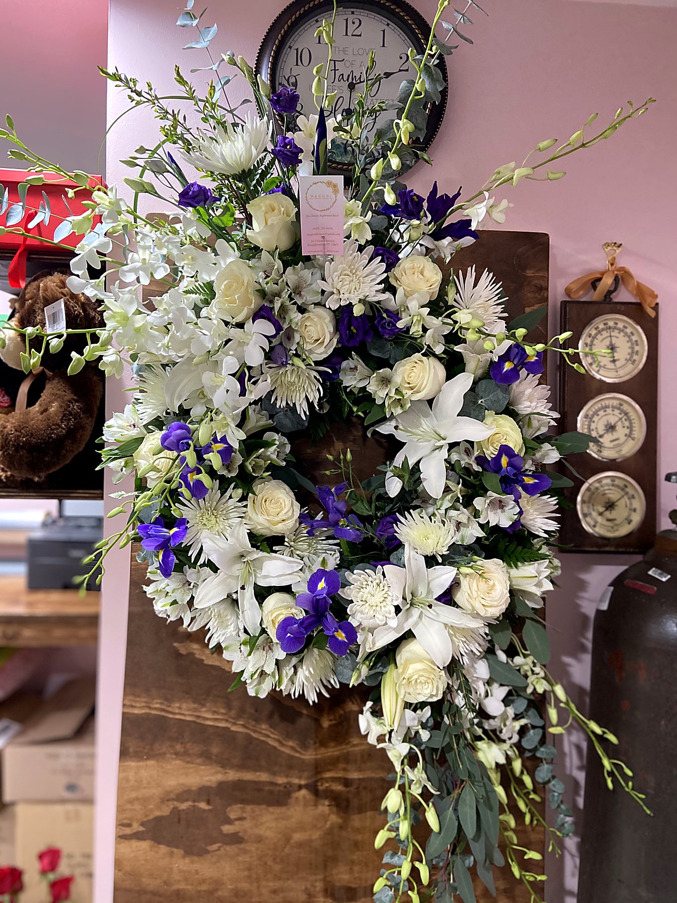 Wreath of white roses, lilies, and chrysanthemums accented with purple iris