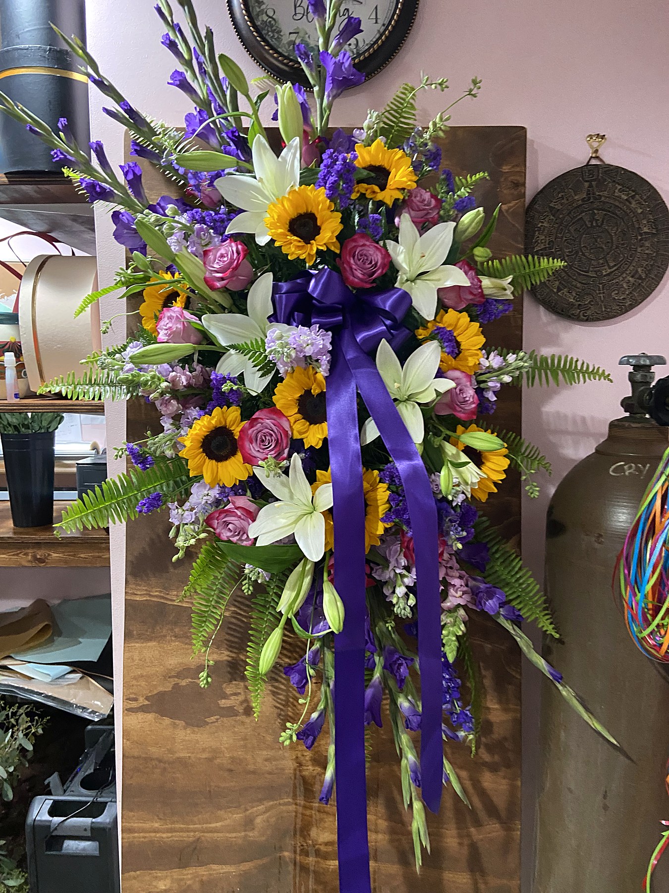 Standing spray of sunflowers, purple delphinium, and blue accents