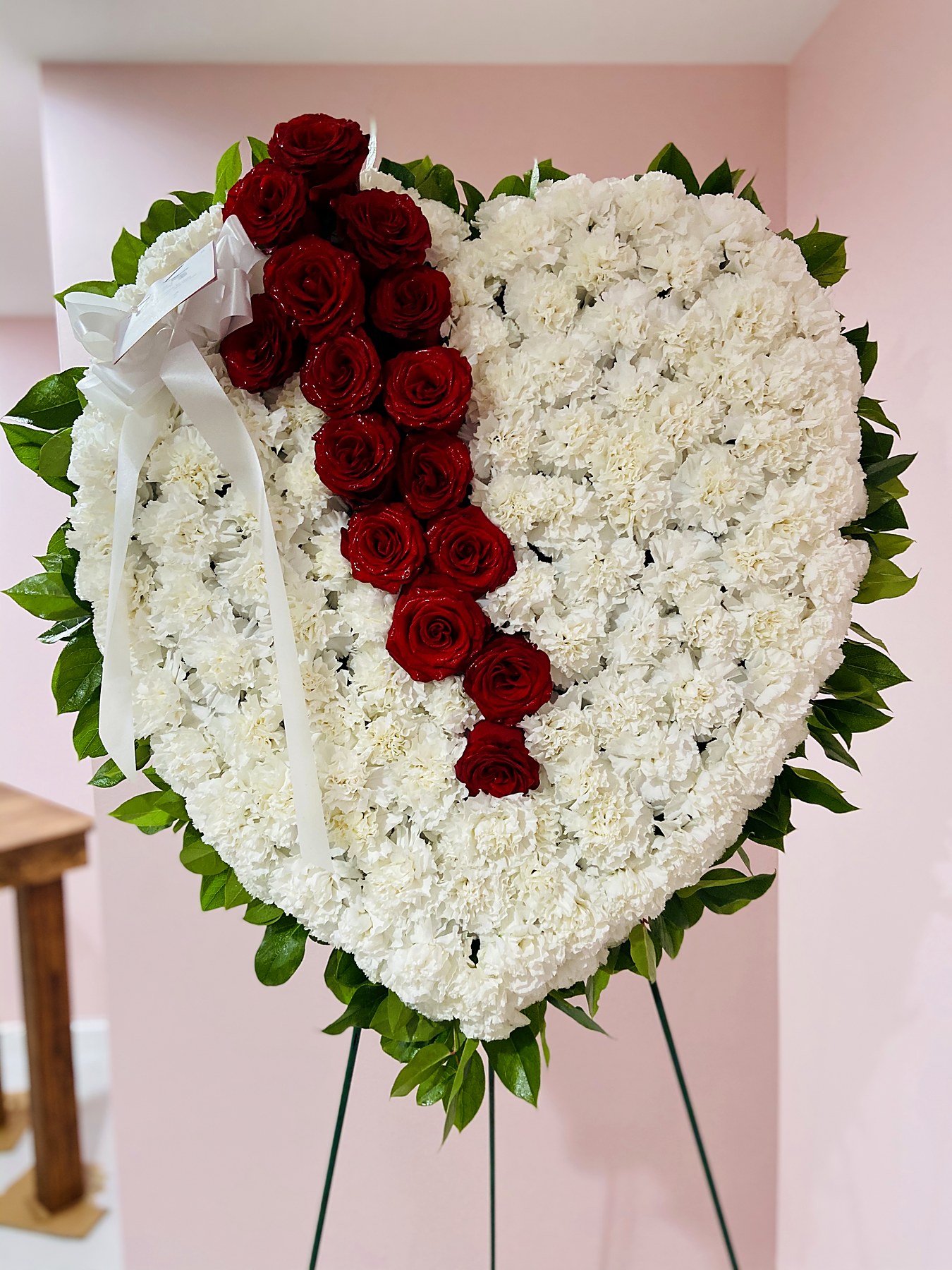 Heart-shaped tribute of white carnations with a diagonal line of red roses