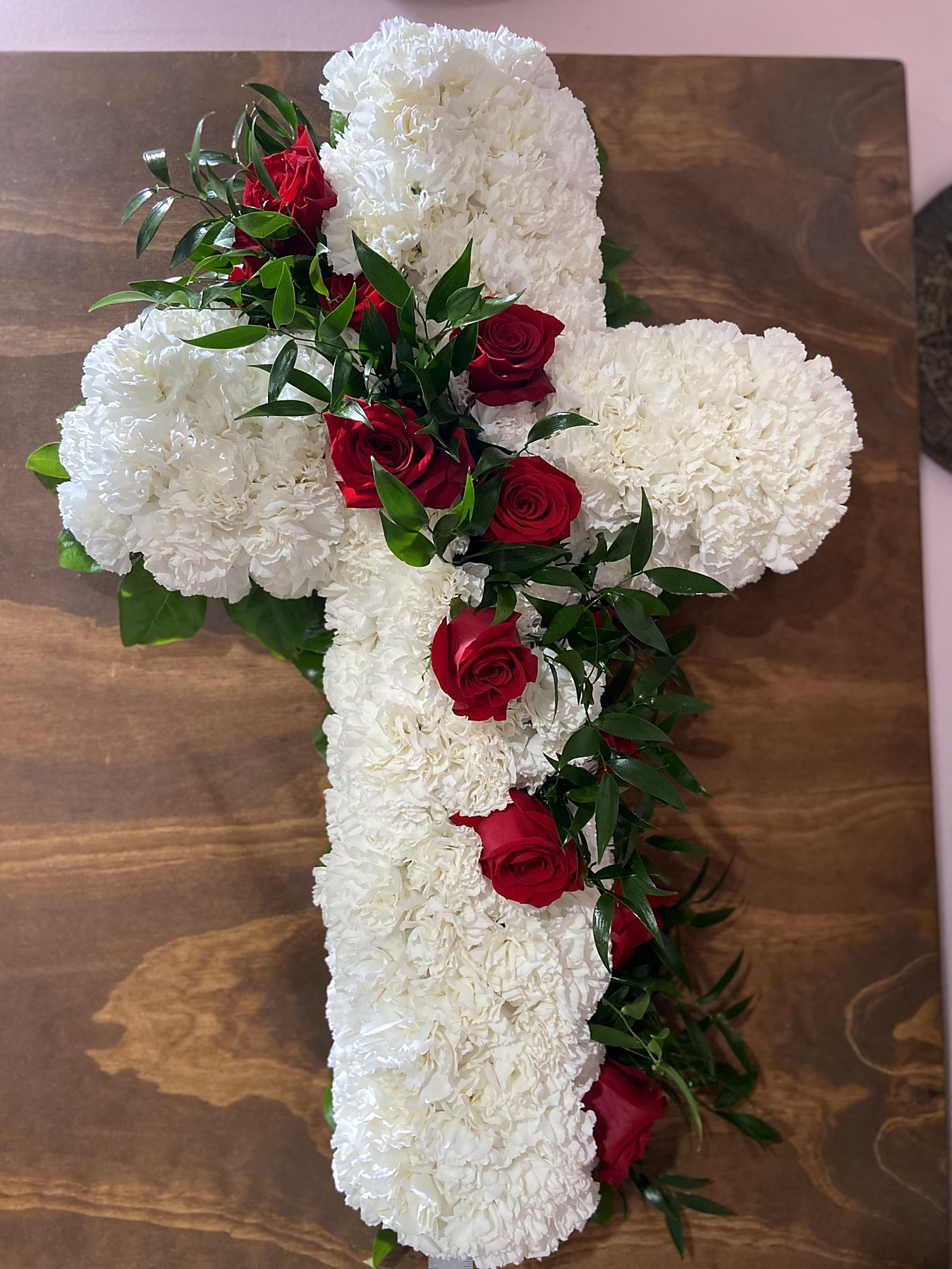 Cross-shaped tribute of white carnations with a line of red roses