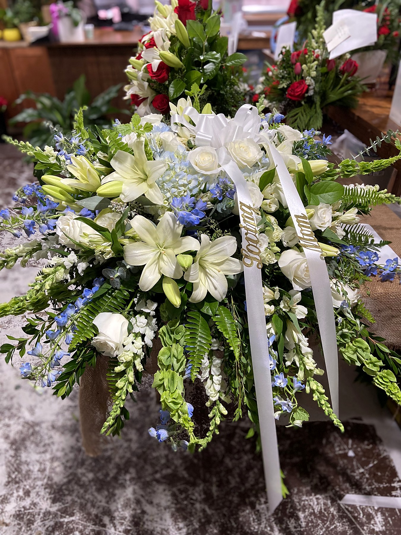 Standing spray of white roses and delphinium with a ribbon