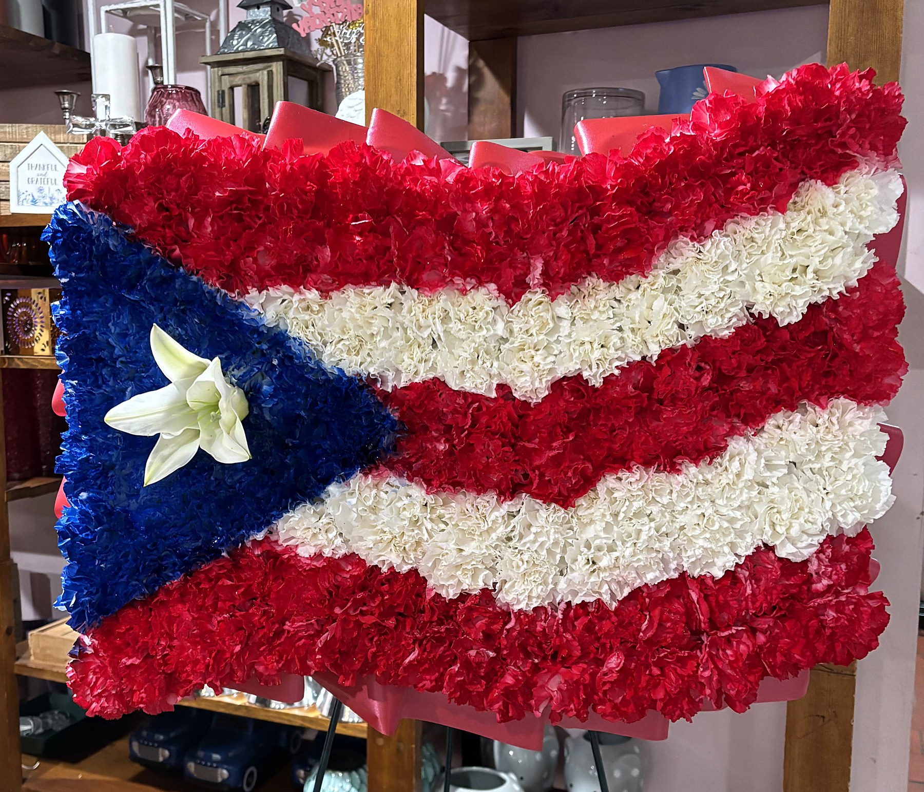 Puerto Rican flag tribute in red, white, and blue carnations with a white lily
