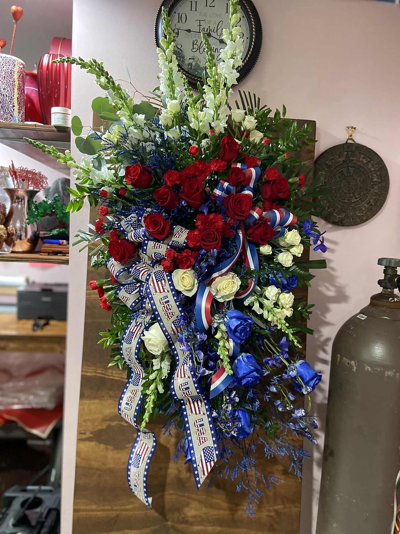 Patriotic standing spray of red, white, and blue roses with a stars-and-stripes ribbon