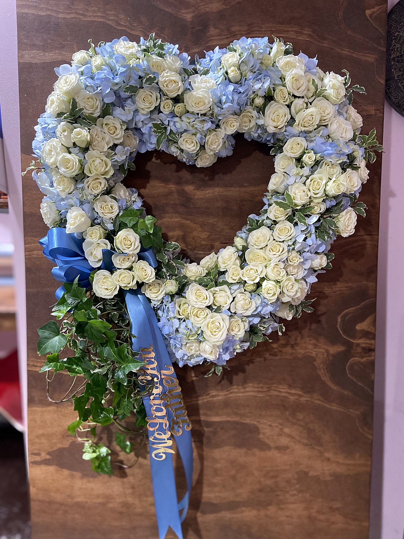 Heart-shaped tribute of white roses and blue hydrangea