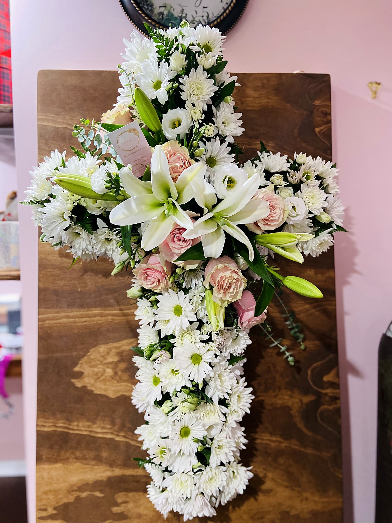 Cross-shaped tribute of white flowers with a gold ribbon